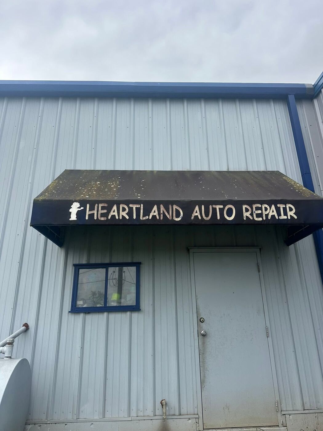 Shop awning before cleaning — heavy green and black staining